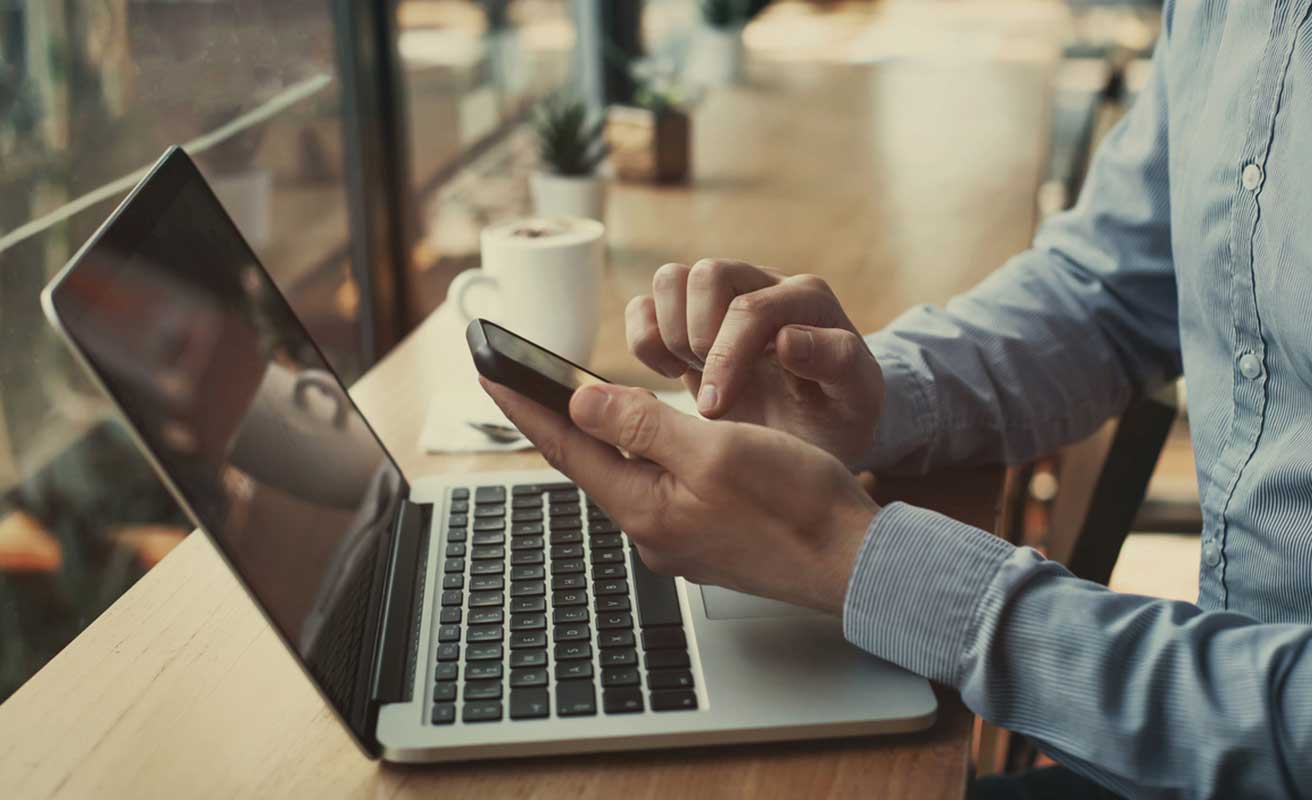 Persona trabajando con el ordenador y el móvil a la vez