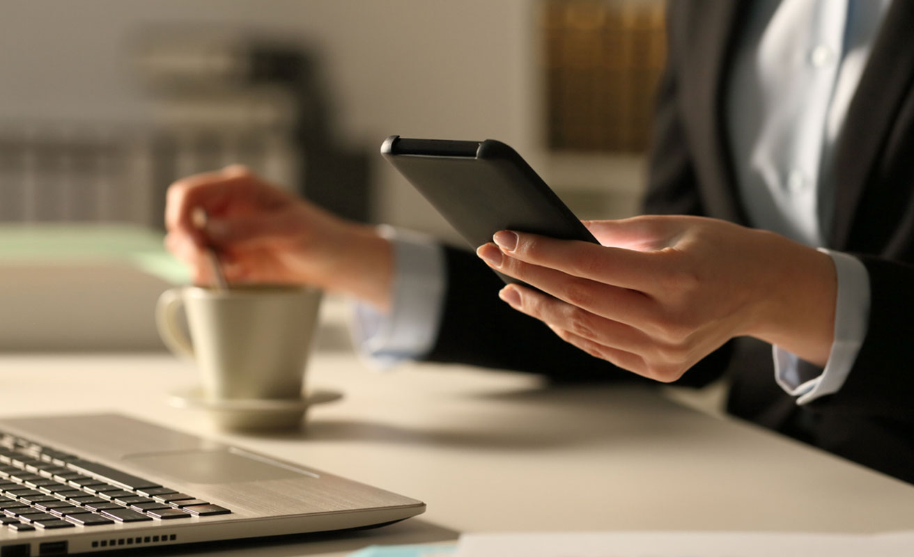 mujer con el móvil en la mano y un café