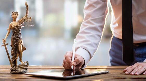 Persona firmando en un iPad al lado de una estatua de Themis