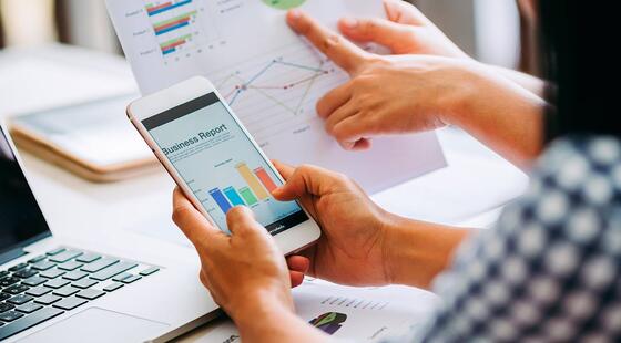 Mujer sosteniendo un teléfono en el que se muestran gráficos