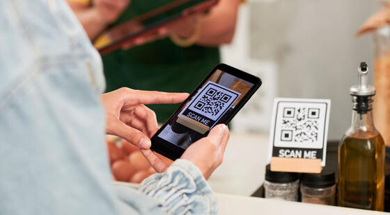 Manos sosteniendo un teléfono móvil utilizando su cámara para escanear un código QR