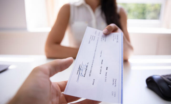 Mujer entregando un cheque firmado