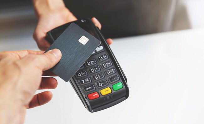 Persona pagando con tarjeta sobre un datáfono o TPV