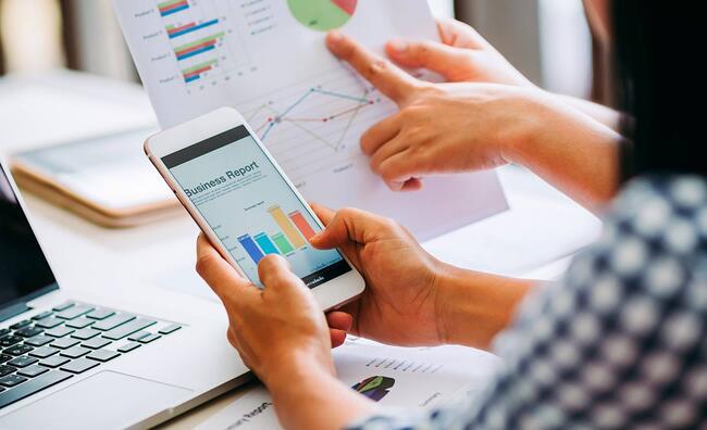 Mujer sosteniendo un teléfono en el que se muestran gráficos