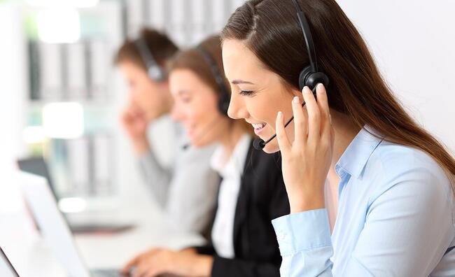 Tres mujeres con auriculares y micrófono sentadas en un escritorio enfrente de un ordenador